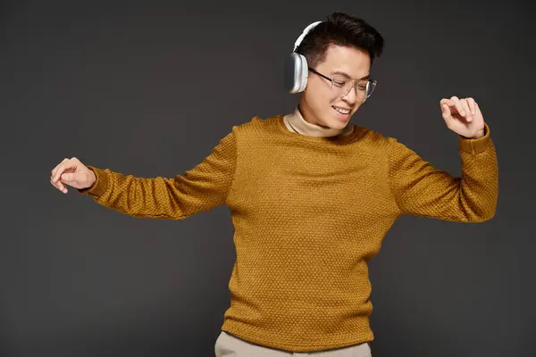 A fashionable young man in a sweater is actively posing while wearing headphones. — Stock Photo