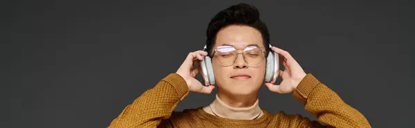 Un joven de moda con gafas y auriculares, activamente comprometido en posar. - foto de stock
