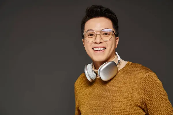 Модний молодий чоловік, одягнений в светр, активно слухає музику через навушники. — стокове фото