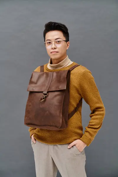 Ein modischer junger Mann in eleganter Kleidung trägt einen braunen Rucksack — Stockfoto