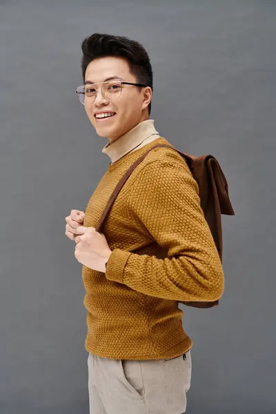 A stylish young man in glasses and a brown sweater poses elegantly. — Stock Photo