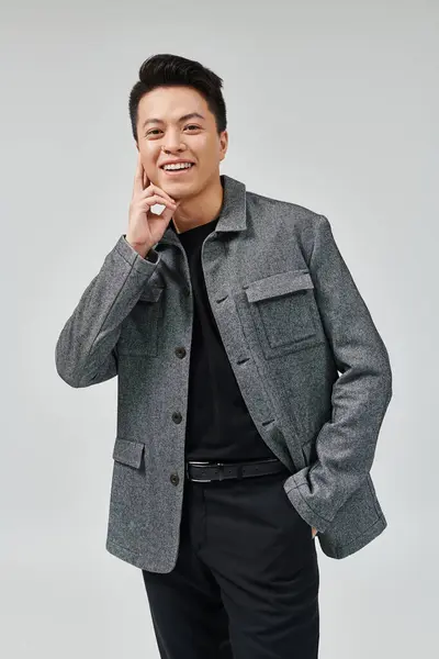 Модний молодий чоловік вражає динамічною позою в стильній сірій куртці і чорній сорочці, виключаючи витонченість і впевненість. — стокове фото