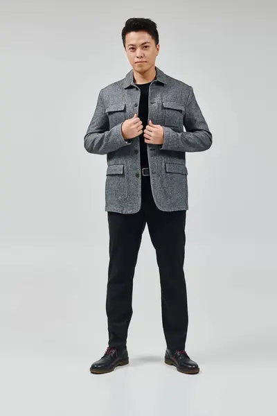 Ein modischer junger Mann in eleganter Kleidung steht selbstbewusst vor hellem Hintergrund — Stockfoto