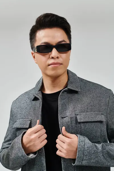 Ein modischer junger Mann posiert selbstbewusst mit Sonnenbrille und stylischem Sakko. — Stockfoto