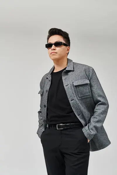 Ein modischer junger Mann posiert aktiv in grauer Jacke und schwarzem Hemd. — Stockfoto