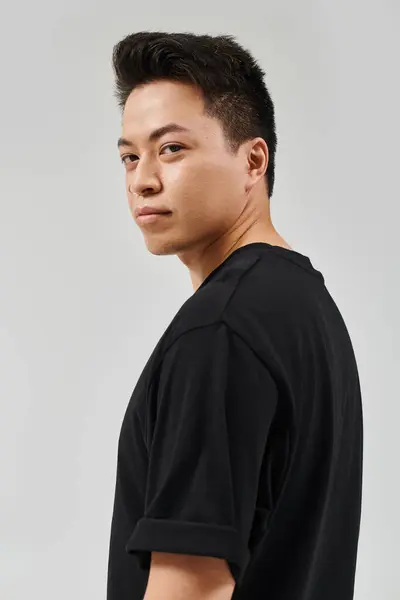 Ein modischer junger Mann im eleganten schwarzen Hemd posiert selbstbewusst für ein stilvolles Foto. — Stockfoto