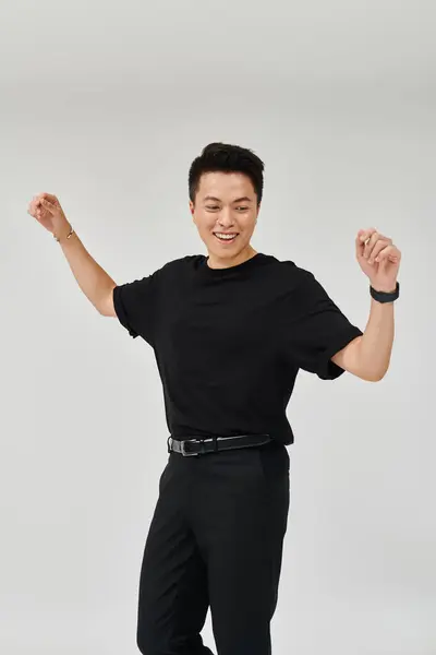 Um jovem elegante em uma camisa preta e calças golpeia uma pose dinâmica, exalando confiança e sofisticação. — Fotografia de Stock