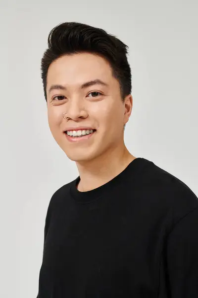 Ein modischer junger Mann mit schwarzem Hemd posiert mit einem fröhlichen Lächeln im Gesicht. — Stockfoto