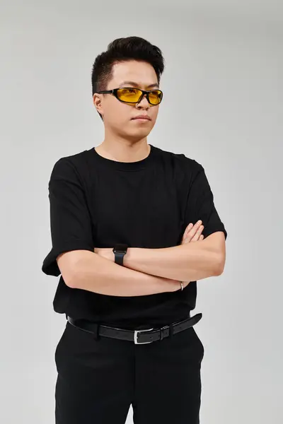 Um jovem elegante faz uma pose em uma camisa preta elegante e óculos de sol elegantes. — Fotografia de Stock