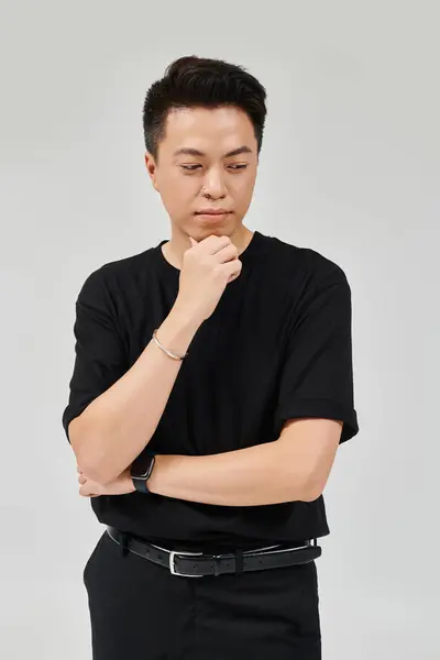 Ein modischer junger Mann in schwarzem Hemd und schwarzer Hose nimmt eine dynamische Pose ein. — Stockfoto