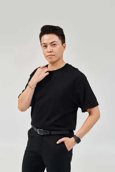 Un joven de moda con una camisa negra y pantalones en una pose dinámica. - foto de stock