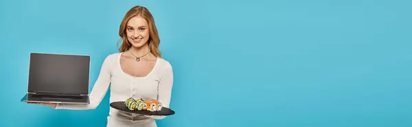 A blonde woman balances sushi on a plate while holding laptop, embodying a modern foodie lifestyle. — Stock Photo