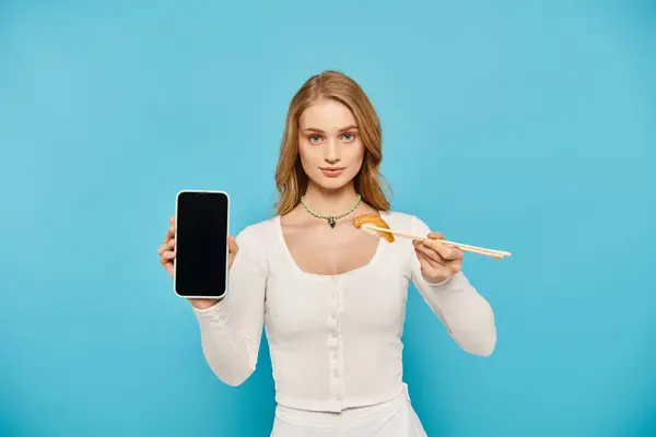 Una donna elegante con i capelli biondi in possesso di una bacchetta e telefono cellulare allo stesso tempo. — Foto stock