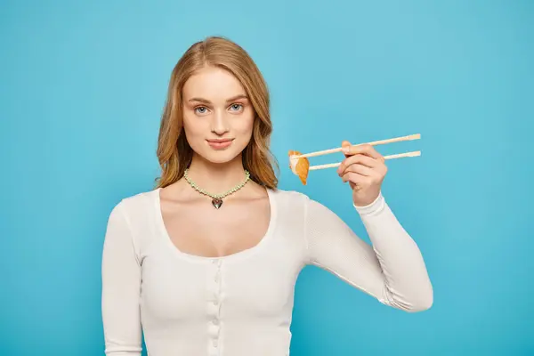 A blonde woman elegantly holds chopsticks and a delectable piece of Asian cuisine. — Stock Photo