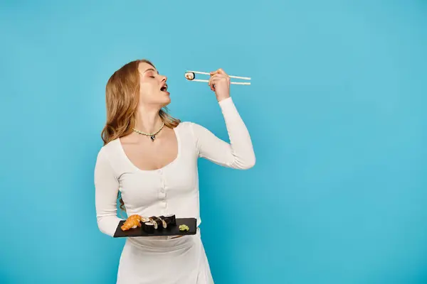Eine schöne Frau in einem weißen Kleid hält elegant ein Tablett mit leckerem asiatischem Essen in der Hand. — Stockfoto