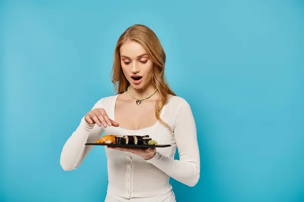 Stunning blonde woman holding a plate of delectable Asian cuisine. — Stock Photo