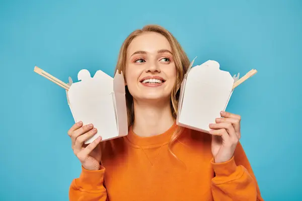 A beautiful woman holds two food boxes in front of her face, showcasing her creativity and mystery. — Stock Photo