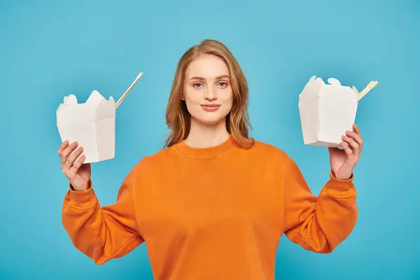 Женщина держит перед лицом две коробки с азиатской едой — стоковое фото