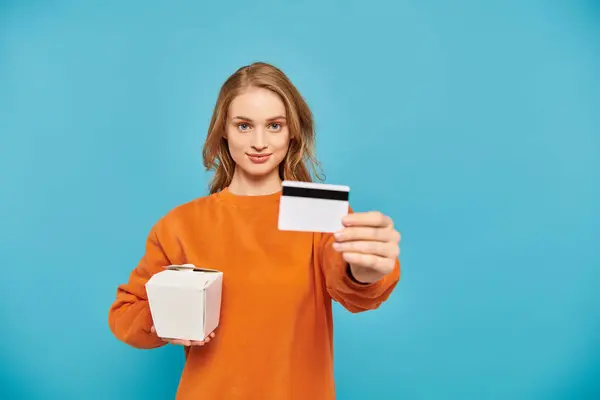 Femme élégante tenant une carte de crédit et une boîte de nourriture asiatique. — Photo de stock