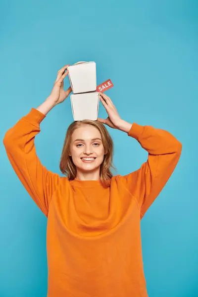 A beautiful blonde woman elegantly balances a food box on her head, showcasing Asian cuisine and culture. — Stock Photo