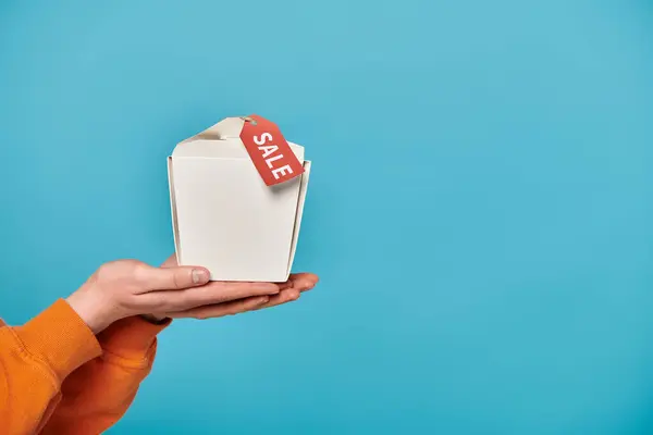 Vista ritagliata della donna tiene scatola di cibo con un tag di vendita su di esso, entusiasta di rivelare il suo contenuto. — Foto stock