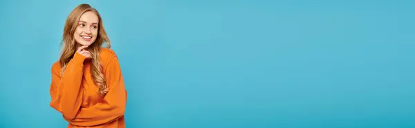 A stunning woman with blonde hair striking a pose while on blue backdrop. — Stock Photo