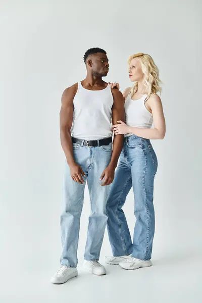 Ein junges multikulturelles Paar steht nebeneinander in einem Atelier vor grauem Hintergrund. — Stockfoto