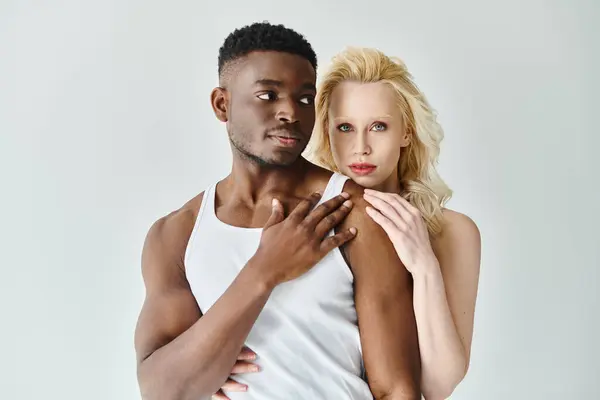 A young multicultural couple joyfully posing for a portrait in a studio against a grey backdrop. — Stock Photo