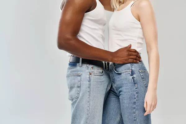 A young multicultural couple standing together in a studio against a grey background. — Stock Photo