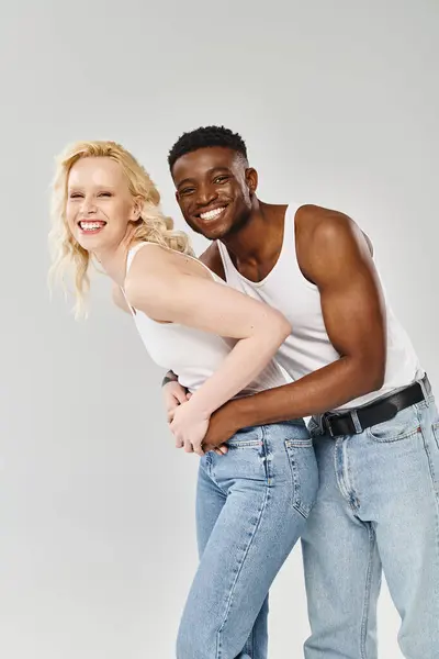 Um jovem casal multicultural faz uma pose dinâmica em um estúdio contra um fundo cinza. — Fotografia de Stock