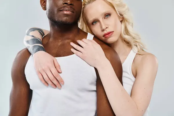 Una joven pareja interracial posando en un estudio sobre un fondo gris. - foto de stock