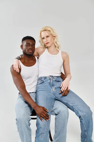 Молода міжрасова пара витончено сидить на стільці в студії, демонструючи єдність і любов. — стокове фото