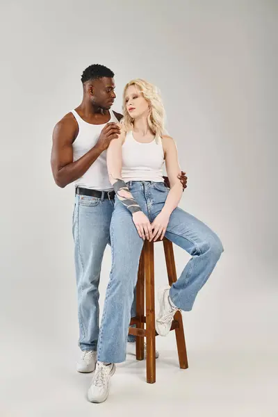 Un uomo sta accanto a una donna che è in piedi su uno sgabello, formando un duo armonioso e dinamico in un ambiente di studio. — Foto stock