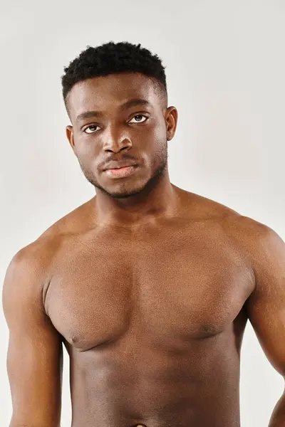A young, shirtless African American man strikes a pose of serenity in a studio against a grey background. — Stock Photo