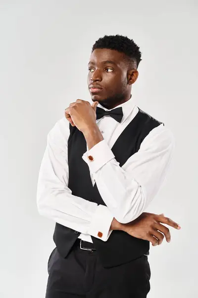 A young, handsome African American groom in a tuxedo striking a confident pose in a studio setting with a grey background. — Stock Photo