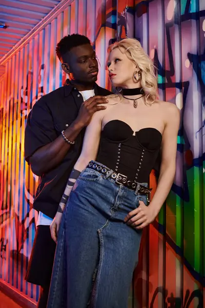 A blonde woman and African American man stand together in an urban street, the woman wearing a corset. — Stock Photo