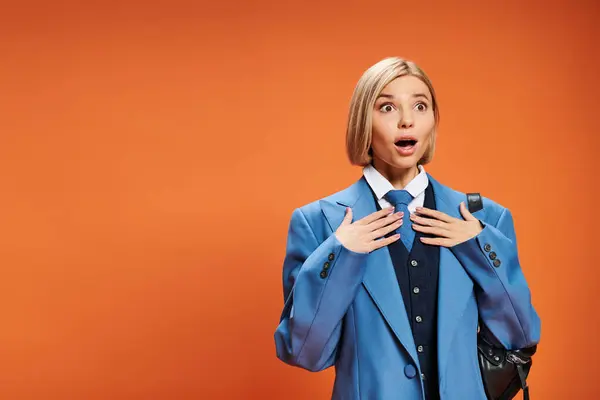 Shocked appealing woman with short blonde hair in sophisticated attire posing on orange backdrop — Stock Photo