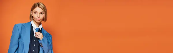 Jolly woman with short blonde hair in elegant attire posing emotionally on orange backdrop, banner — Stock Photo