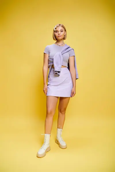 Contented well dressed woman with blonde short hair in vibrant attire posing on yellow backdrop — Stock Photo