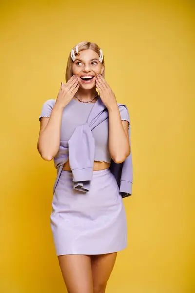 Joyful well dressed woman with blonde short hair in vibrant attire posing on yellow backdrop — Stock Photo