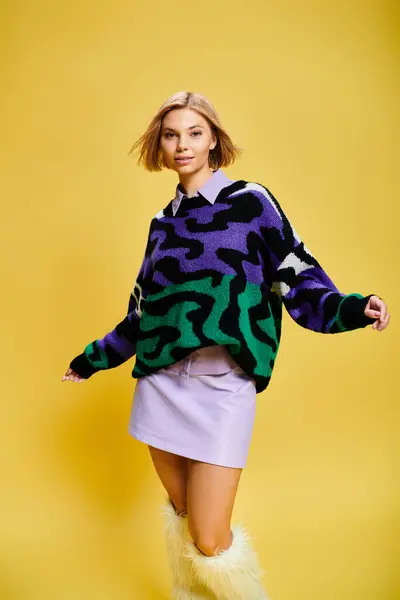 Alegre mujer de buen aspecto con el pelo corto en suéter vibrante posando activamente sobre el fondo amarillo — Stock Photo