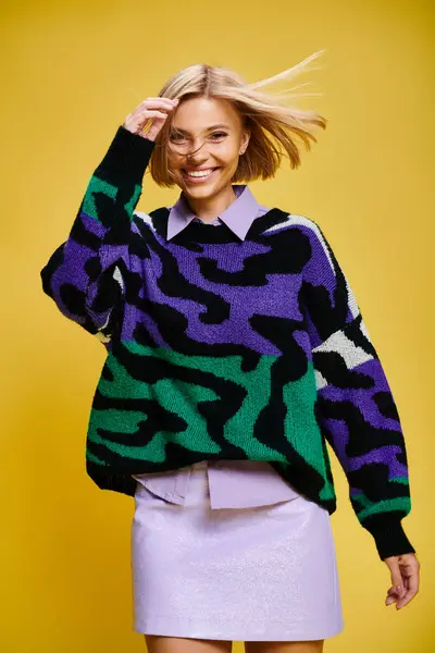 Contented good looking woman with short hair in vibrant sweater posing actively on yellow backdrop — Stock Photo