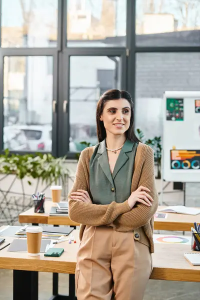 Eine Frau in einem kreativen Büroraum sprüht vor Inspiration, als sie vor einem rustikalen Holztisch steht. — Stockfoto