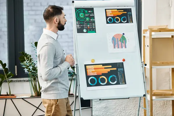 Un hombre en traje de oficina de pie frente a una pizarra blanca, presentando activamente ideas durante una reunión corporativa. — Stock Photo