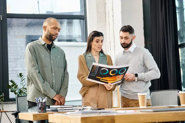 A diverse group of professionals stand around a table, engrossed in a magazine, brainstorming ideas for a project in an office setting. — Stock Photo