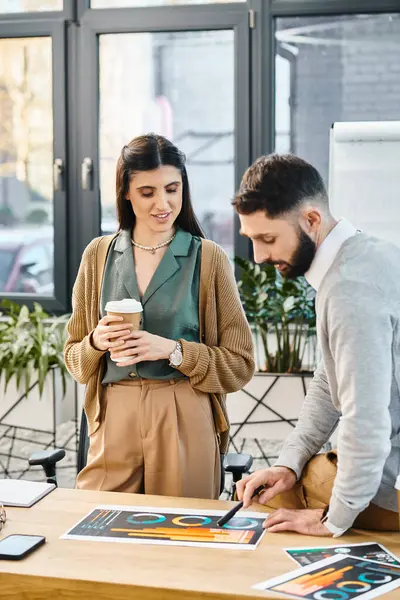 A man and a woman reminiscing over memories captured in photos spread out on a table in an office setting. — Stock Photo