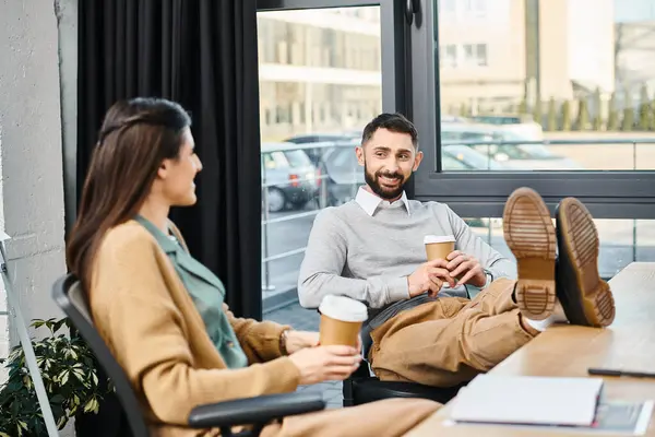 A couple enjoys a quiet moment together at a table, savoring cups of coffee in a serene office setting. — Stock Photo
