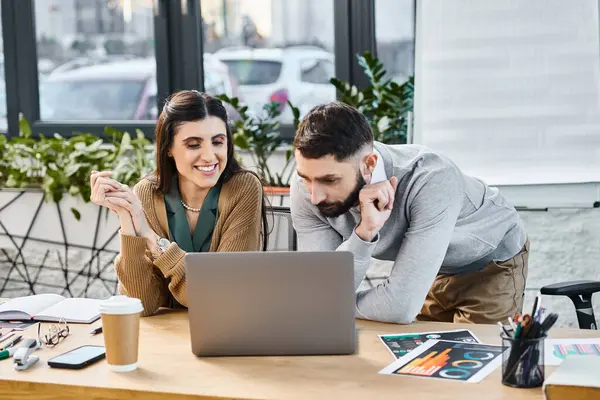Um homem e uma mulher em um escritório corporativo se concentram intensamente em sua tela de laptop, trabalhando juntos em um projeto. — Fotografia de Stock