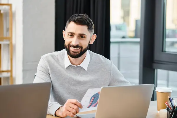 A man immersed in work, sits in front of a laptop in a bustling office, embodying the modern corporate culture. — Stock Photo
