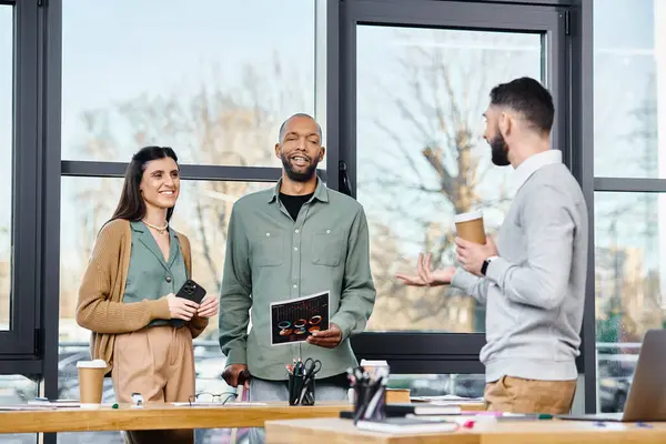 A diverse group of professionals standing around a table, engaged in lively discussion and brainstorming for a project in a corporate office setting. — Stock Photo